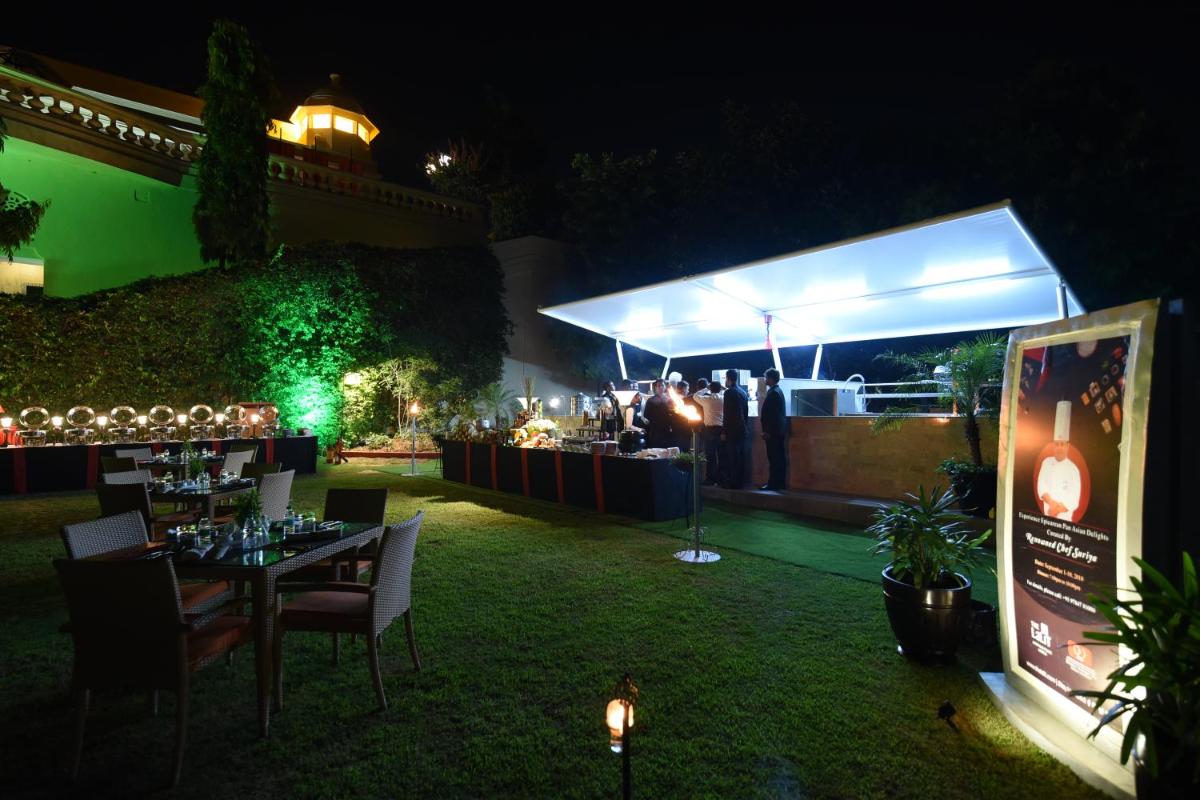a party with a table and chairs in a yard at night at The Lalit Laxmi Vilas Palace in Udaipur