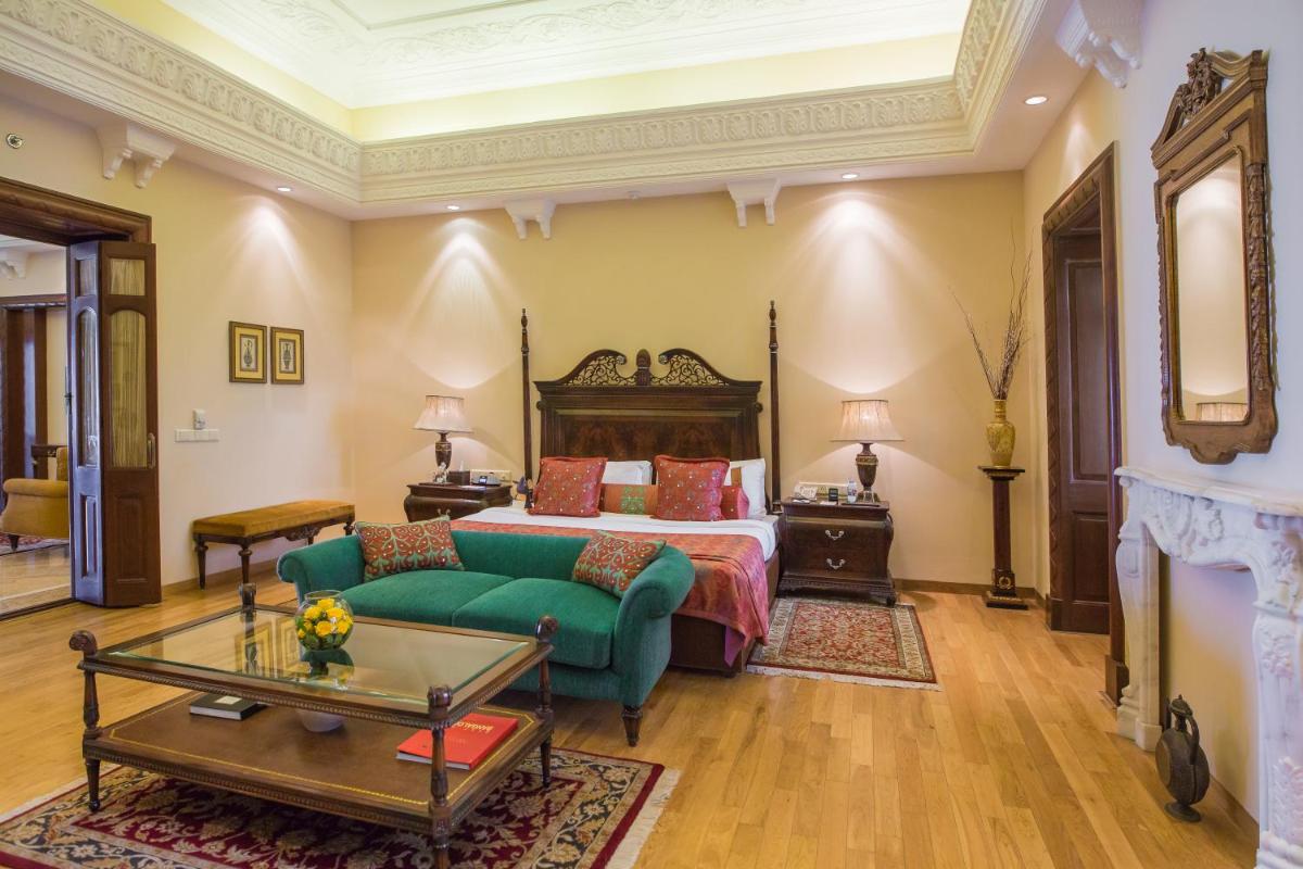 a bedroom with a bed and a green couch at The Lalit Laxmi Vilas Palace in Udaipur