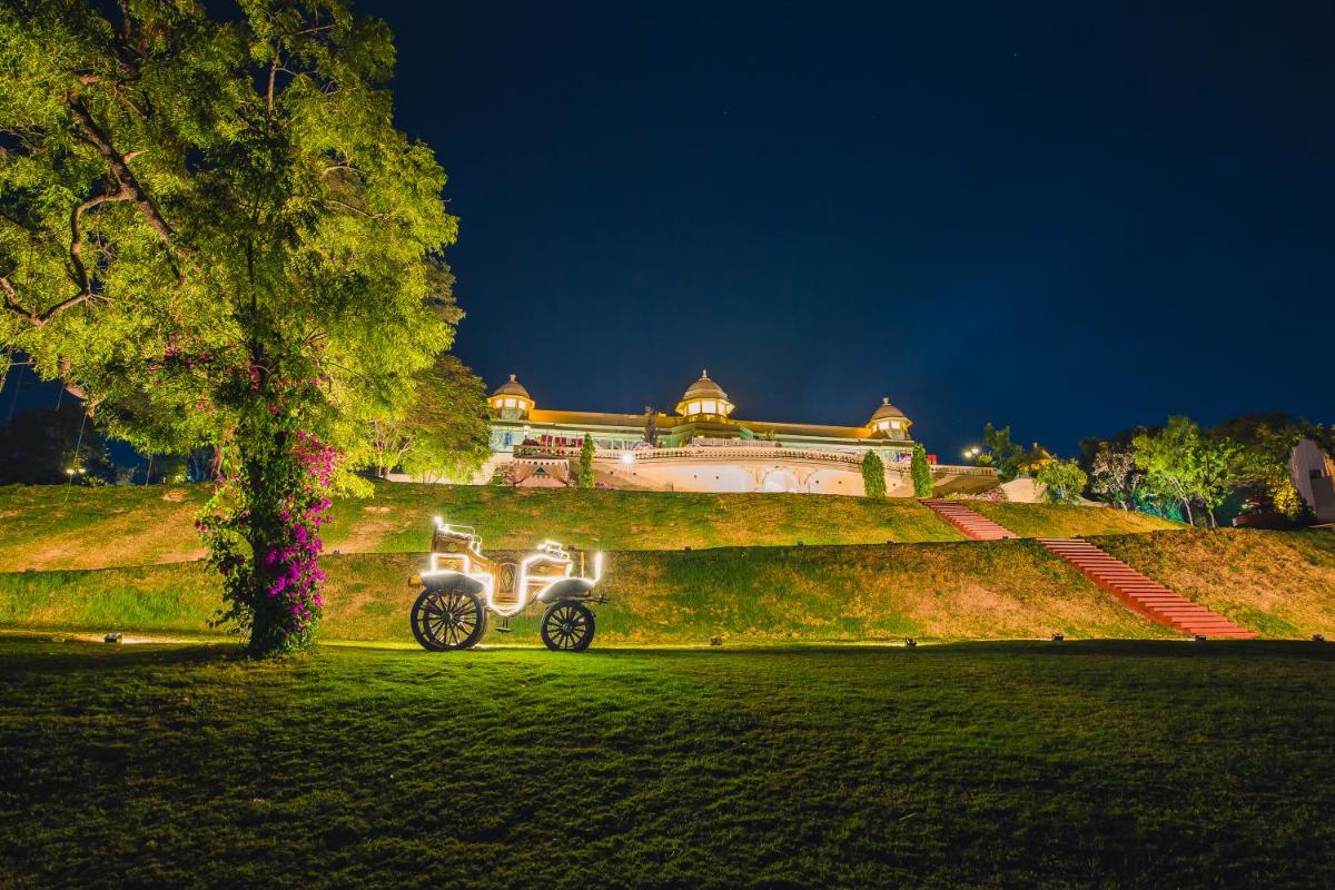 a scooter parked in a field in front of a building at The Lalit Laxmi Vilas Palace in Udaipur