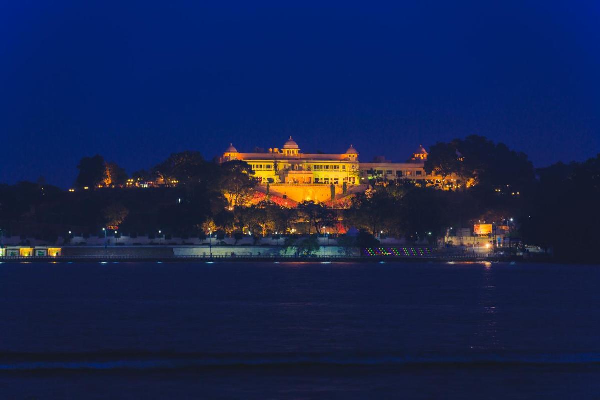 a large building on a hill next to the water at night at The Lalit Laxmi Vilas Palace in Udaipur