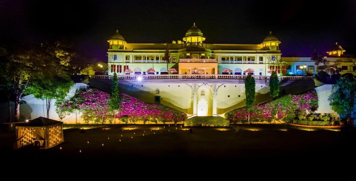 a large building with flowers in front of it at night at The Lalit Laxmi Vilas Palace in Udaipur