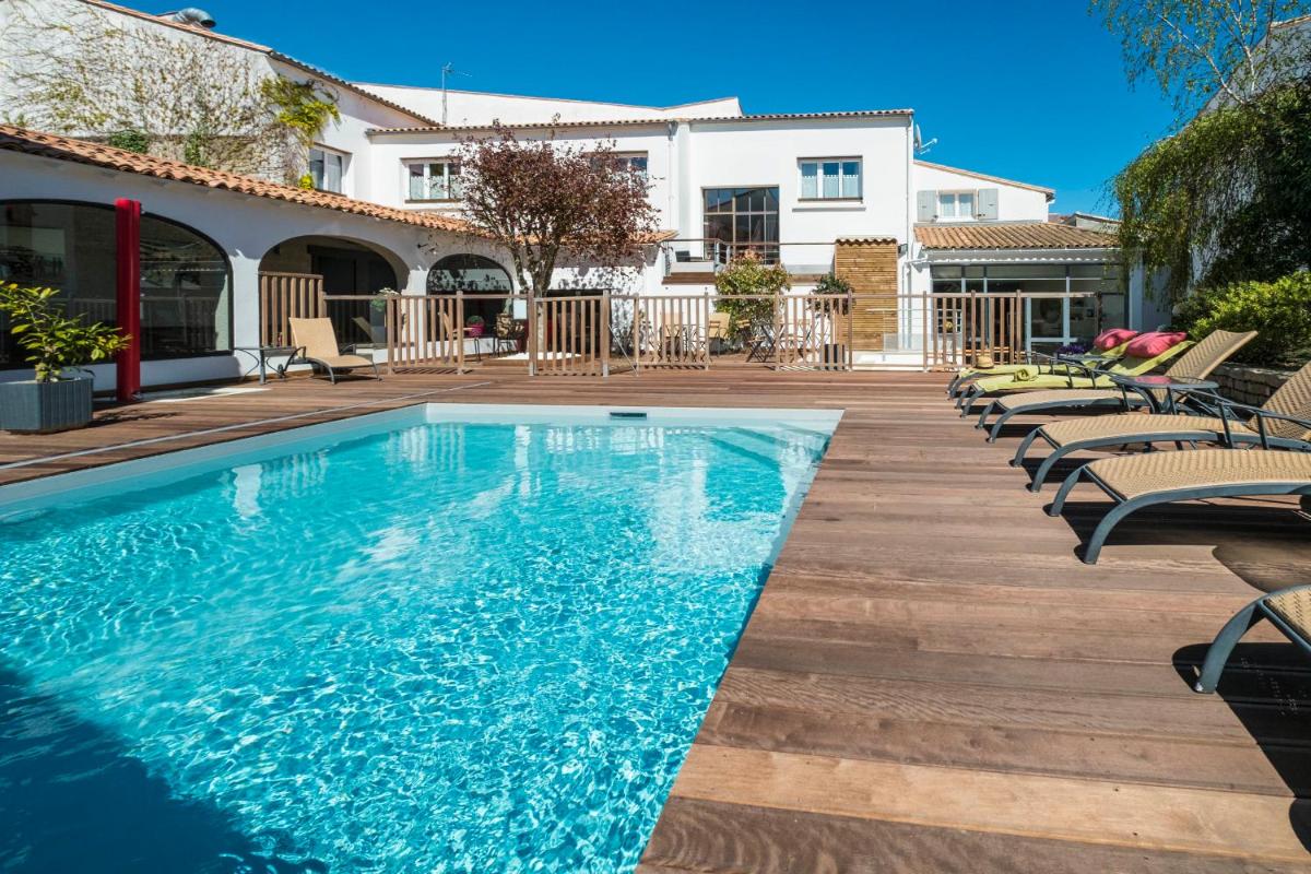 une piscine avec des chaises longues à côté d'une maison dans l'établissement Hôtel de La Marée - Face à l'océan - Ile de Ré, à Rivedoux-Plage
