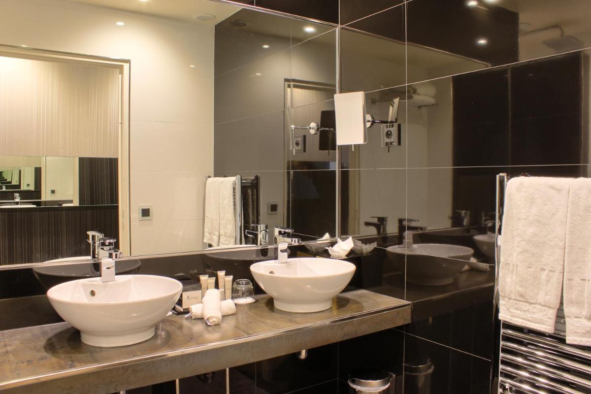 une salle de bains avec deux lavabos et un grand miroir dans l'établissement L'Empire Paris - Louvre, à Paris