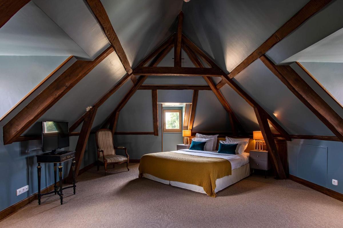 une chambre avec un lit dans les combles dans l'établissement Domaine Du Roncemay - Hôtel, Restaurants, Spa & Golf, à Aillant-sur-Tholon