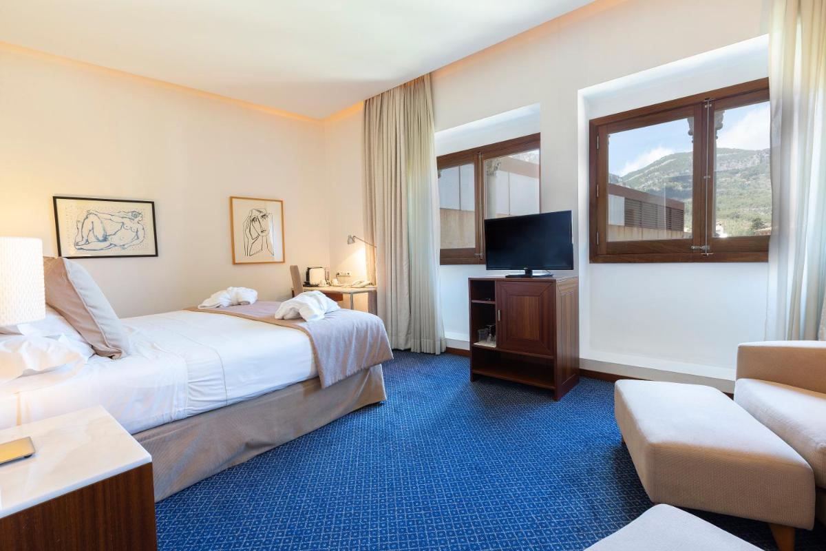 Habitación de hotel con cama, TV y sofá en Gran Hotel Soller, en Sóller
