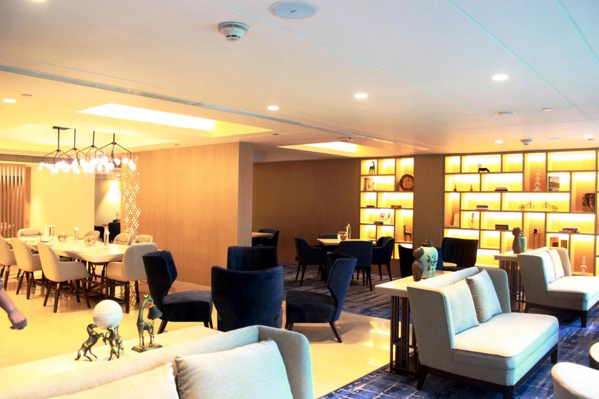 a restaurant with couches and tables and chairs at Novotel Ahmedabad in Ahmedabad
