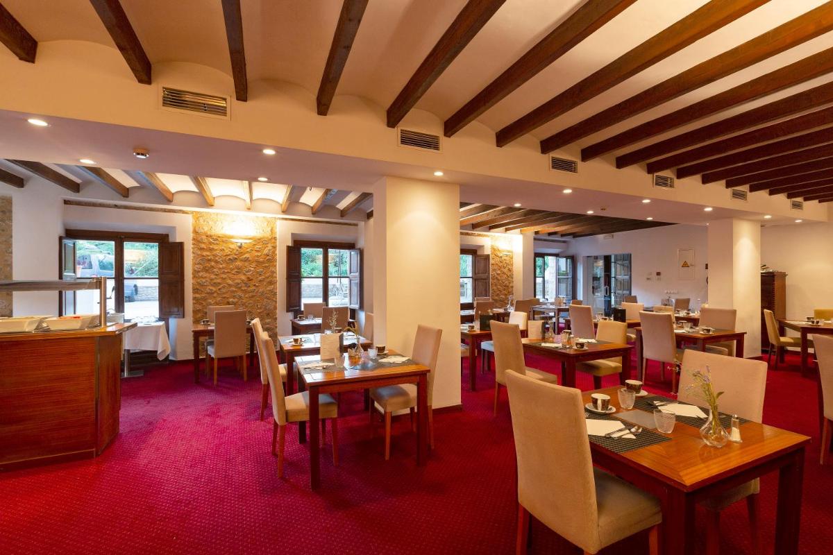 Un comedor con mesas y sillas de madera. en Gran Hotel Soller, en Sóller