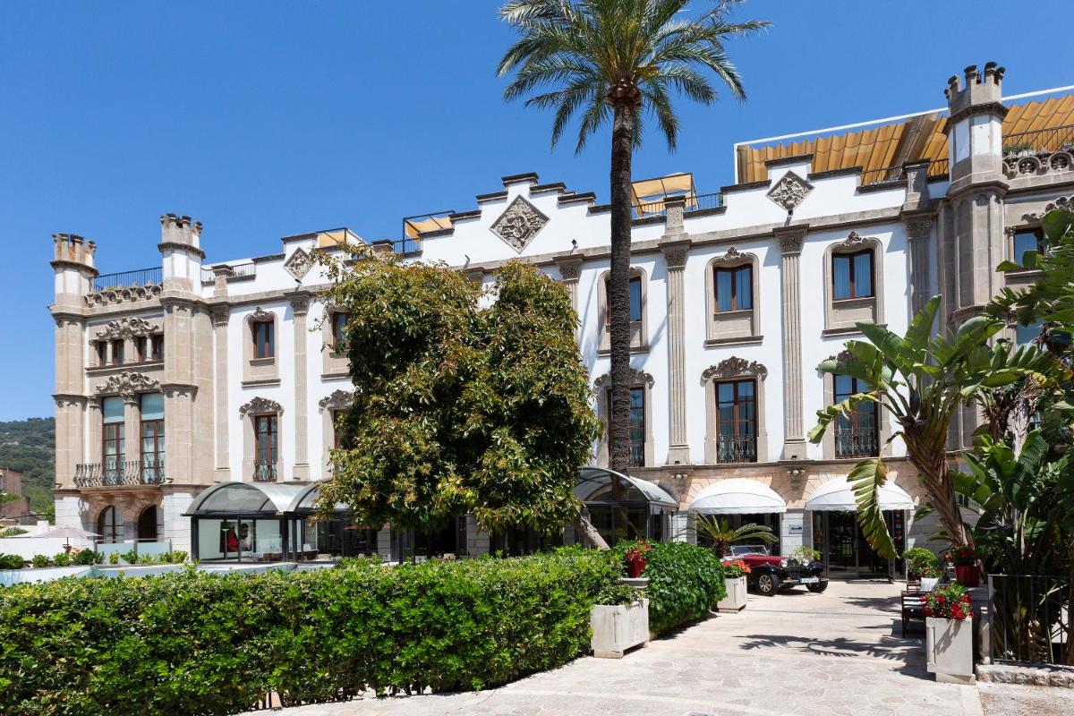 Un gran edificio con una palmera delante. en Gran Hotel Soller, en Sóller