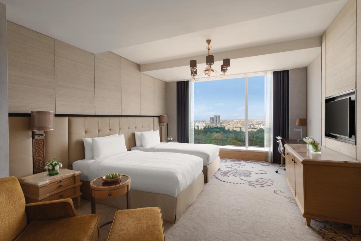 a hotel room with a bed and a large window at Shangri-La Bengaluru in Bengaluru a hotel room with a bed and a large window at Shangri-La Bengaluru in Bengaluru