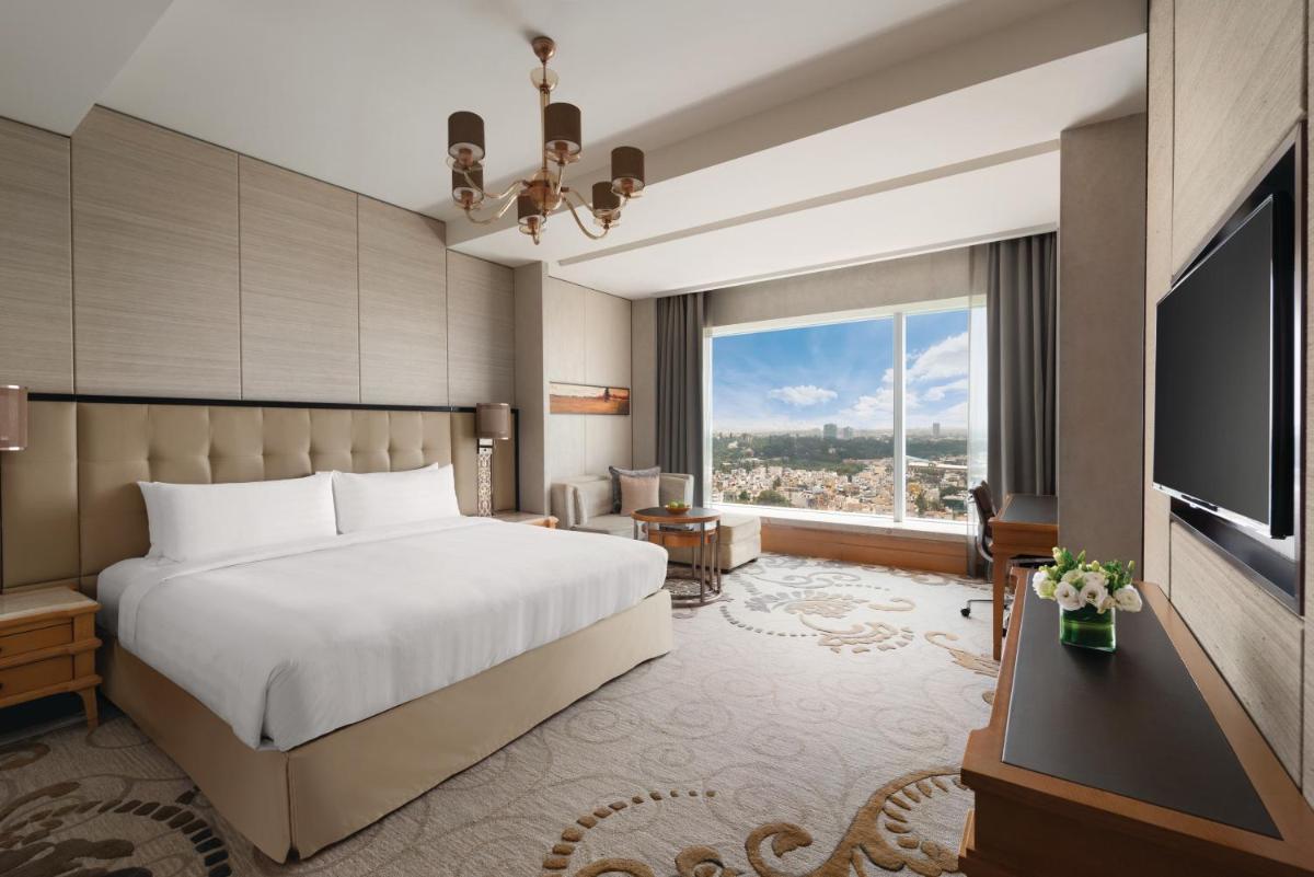 a hotel room with a bed and a large window at Shangri-La Bengaluru in Bengaluru a hotel room with a bed and a large window at Shangri-La Bengaluru in Bengaluru