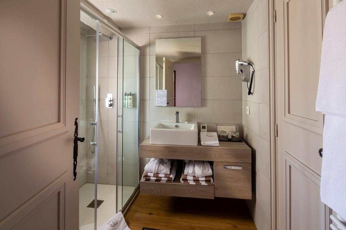 une salle de bain avec un lavabo et une douche en verre dans l'établissement Château et Golf De Taulane, à La Martre