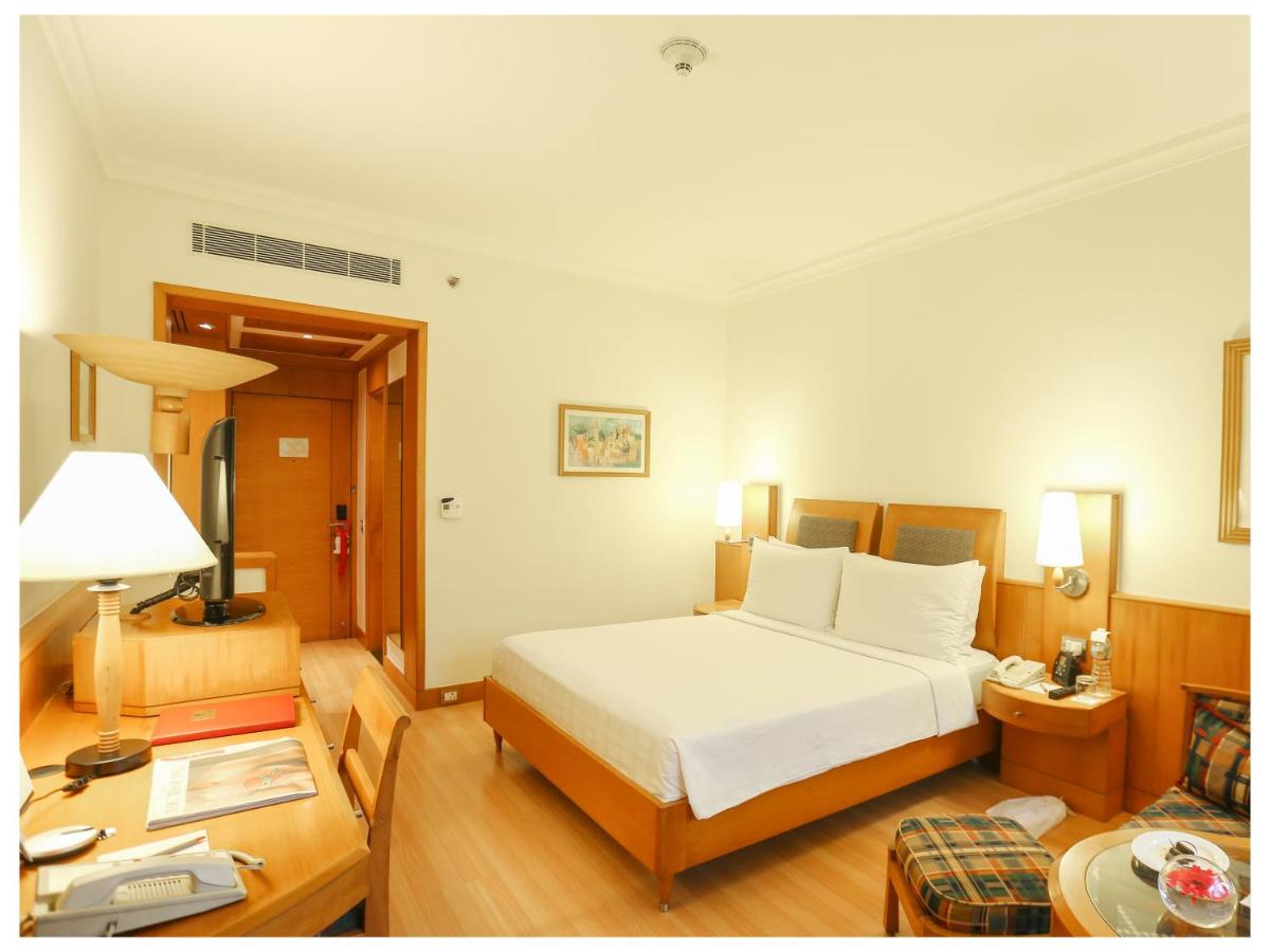a bedroom with a large white bed and a table at Trident Chennai in Chennai