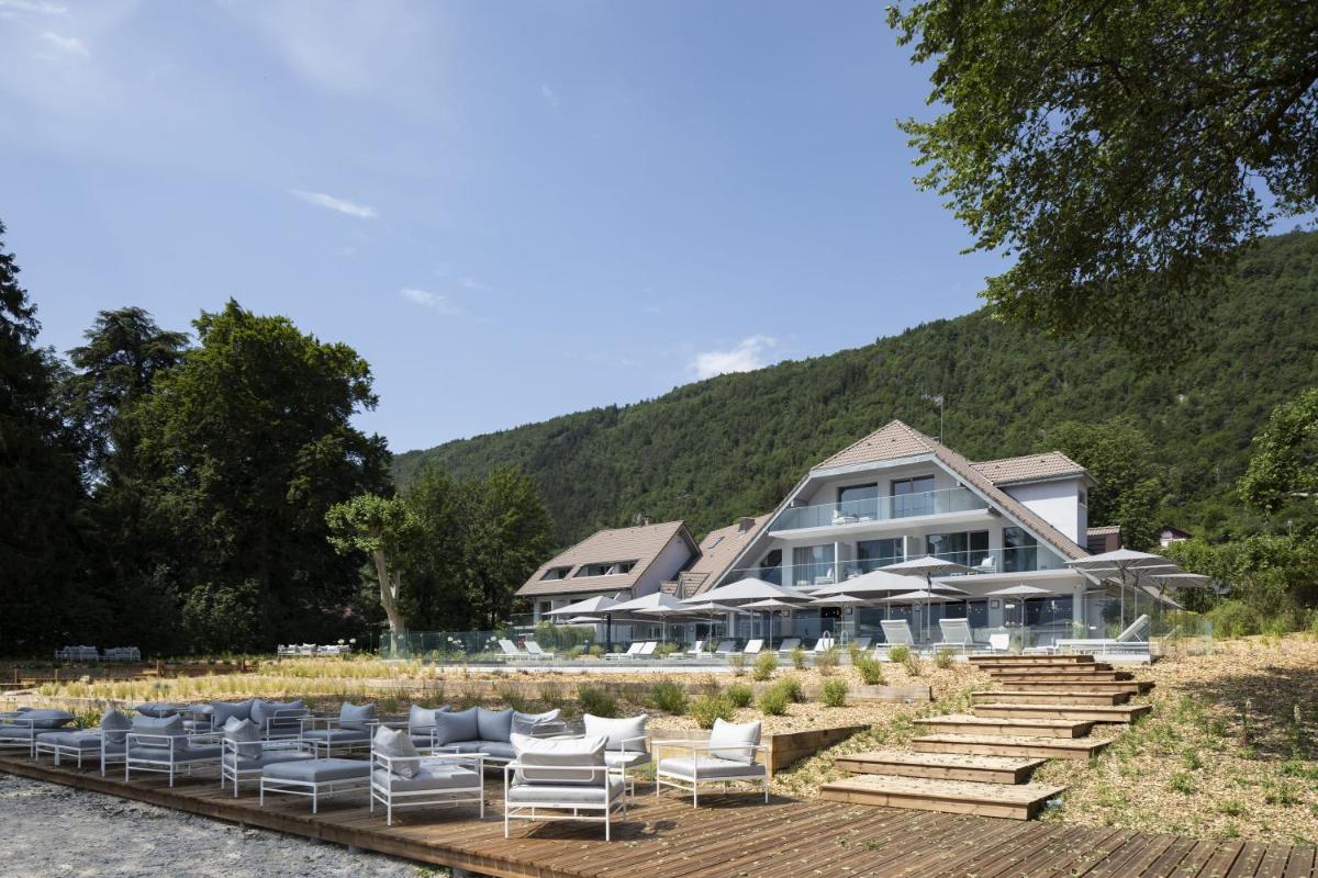 un hôtel avec des chaises et des parasols devant un bâtiment dans l'établissement Black Bass Hotel, à Sévrier