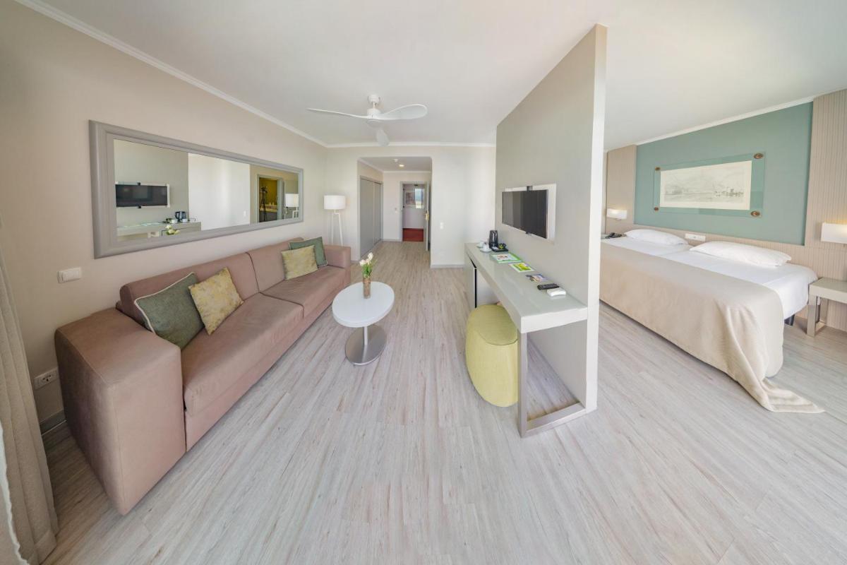 um quarto de hotel com um sofá e uma cama em Hotel Orca Praia no Funchal
