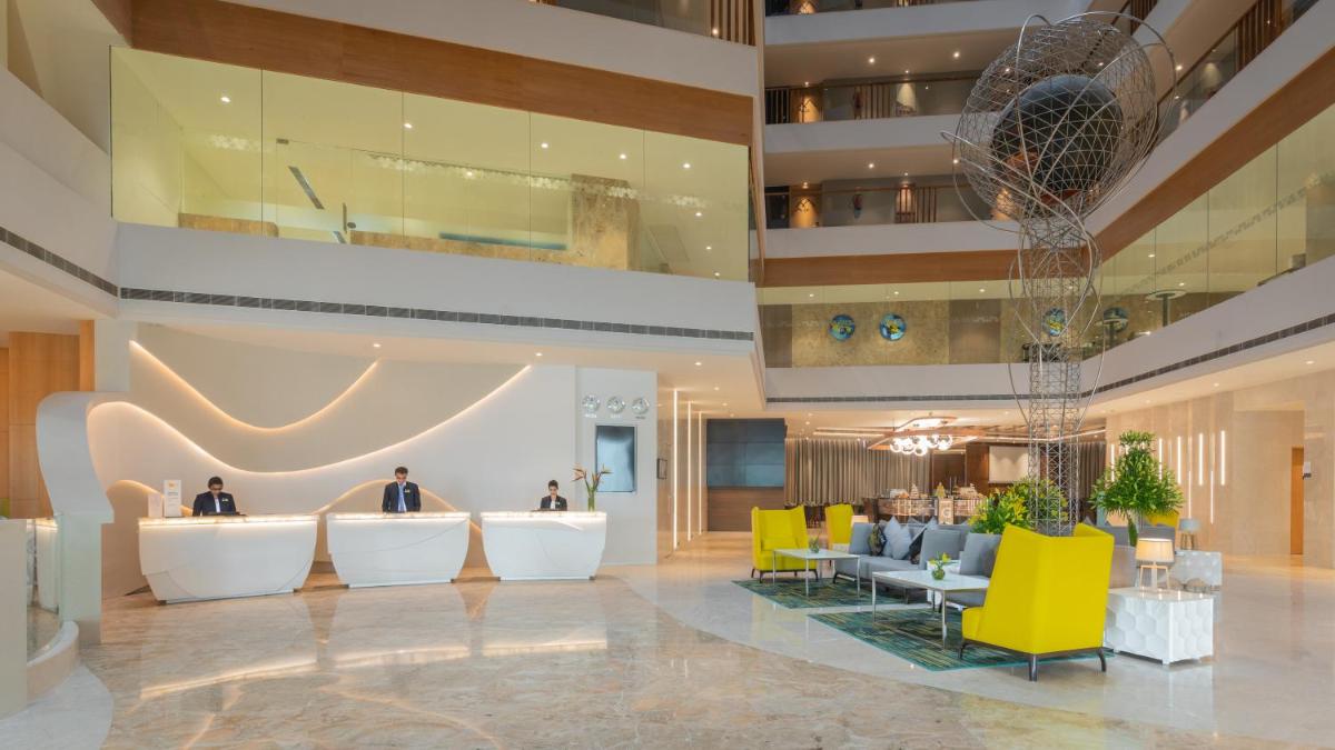 a lobby of a hotel with yellow chairs and tables at Novotel Vijayawada Varun in Vijayawāda