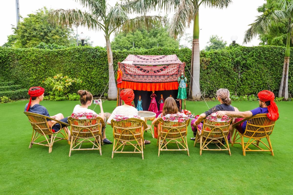 a group of people sitting around a table in the grass at The Grand Imperial - Heritage Hotel in Agra