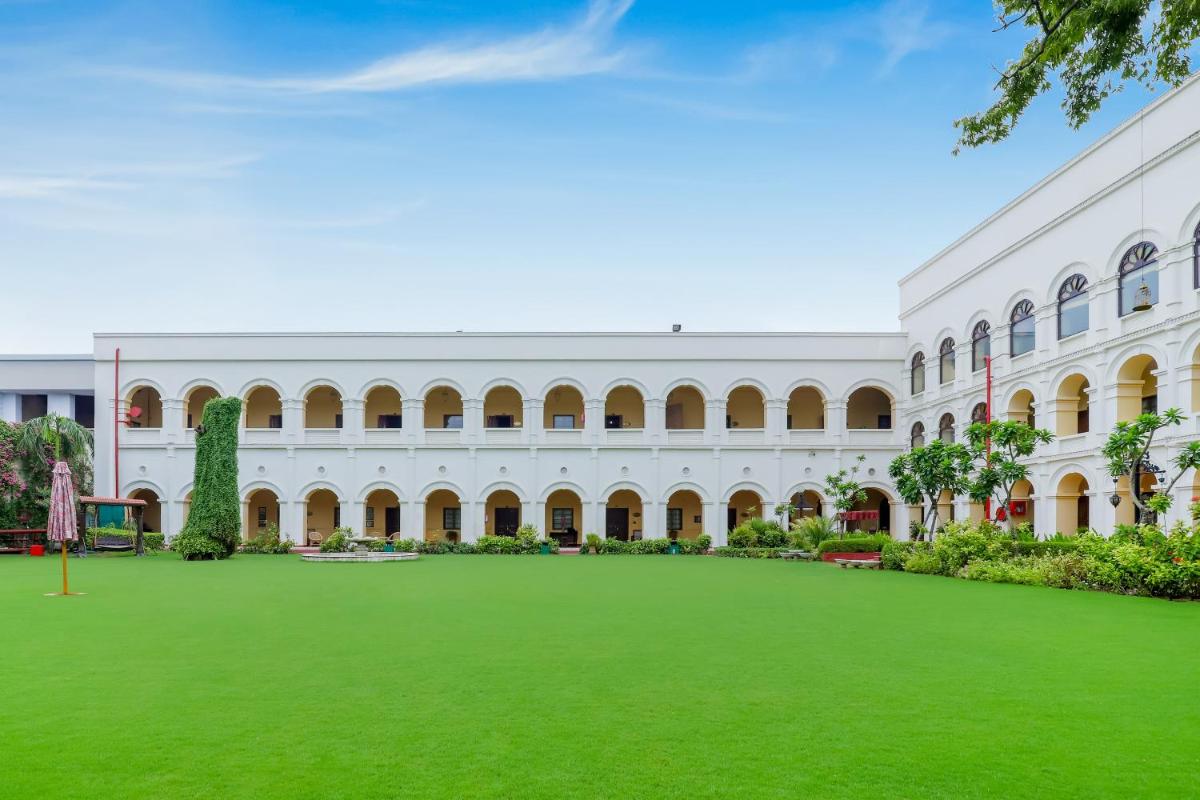 a large white building with a green lawn in front at The Grand Imperial - Heritage Hotel in Agra