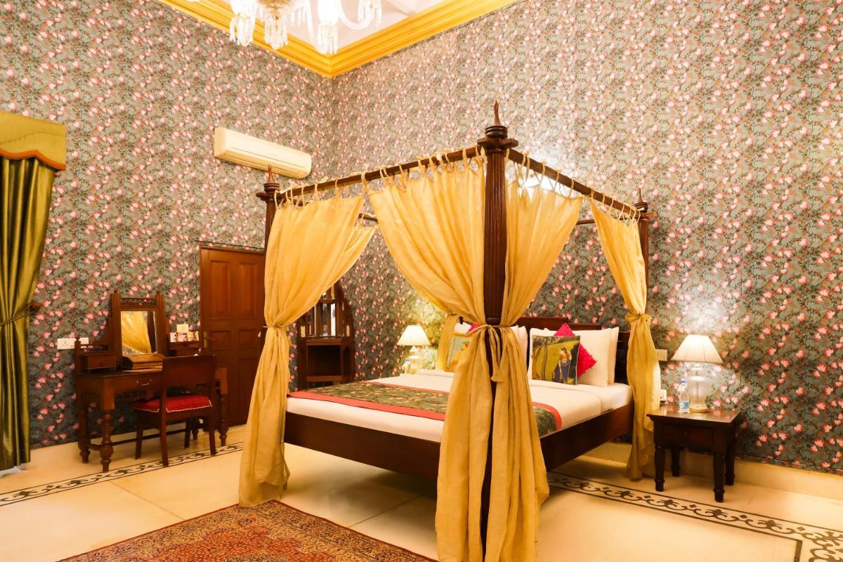a bedroom with a canopy bed in a room with wallpaper at The Grand Imperial - Heritage Hotel in Agra