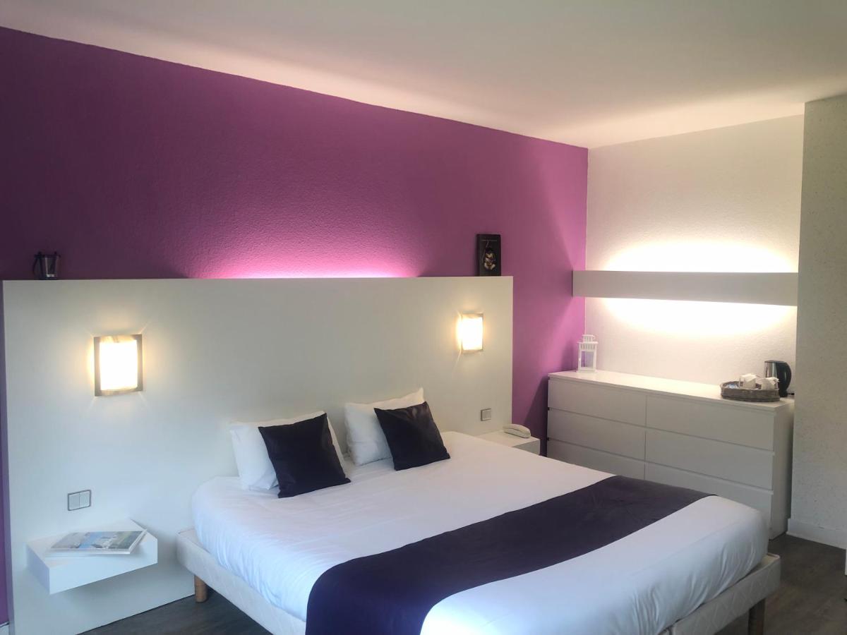 une chambre avec un grand lit aux murs violets dans l'établissement Logis Latitude Ouest Hôtel Restaurant & Spa, à Locronan