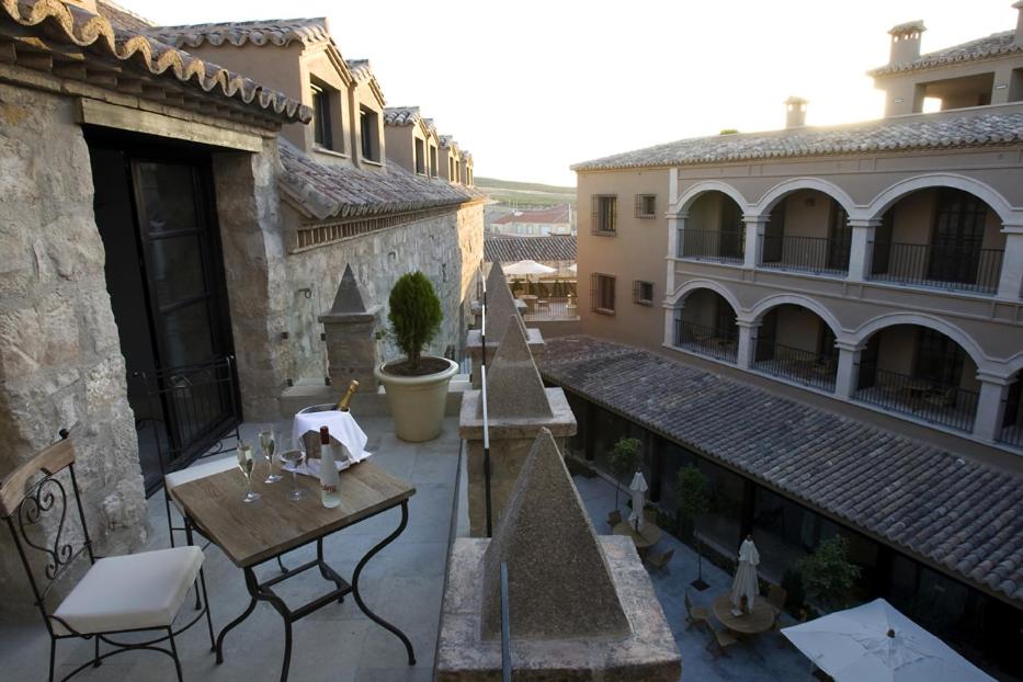 un patio al aire libre con mesas, sillas y edificios en Hotel Palacio de Mengibar, en Mengíbar