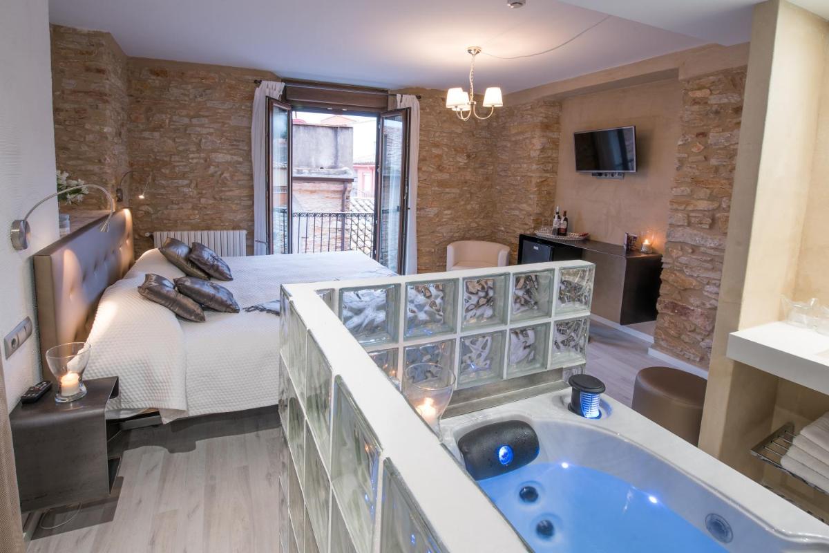 Un baño con bañera y un dormitorio con cama. en Hotel-Spa Classic Begur, en Begur