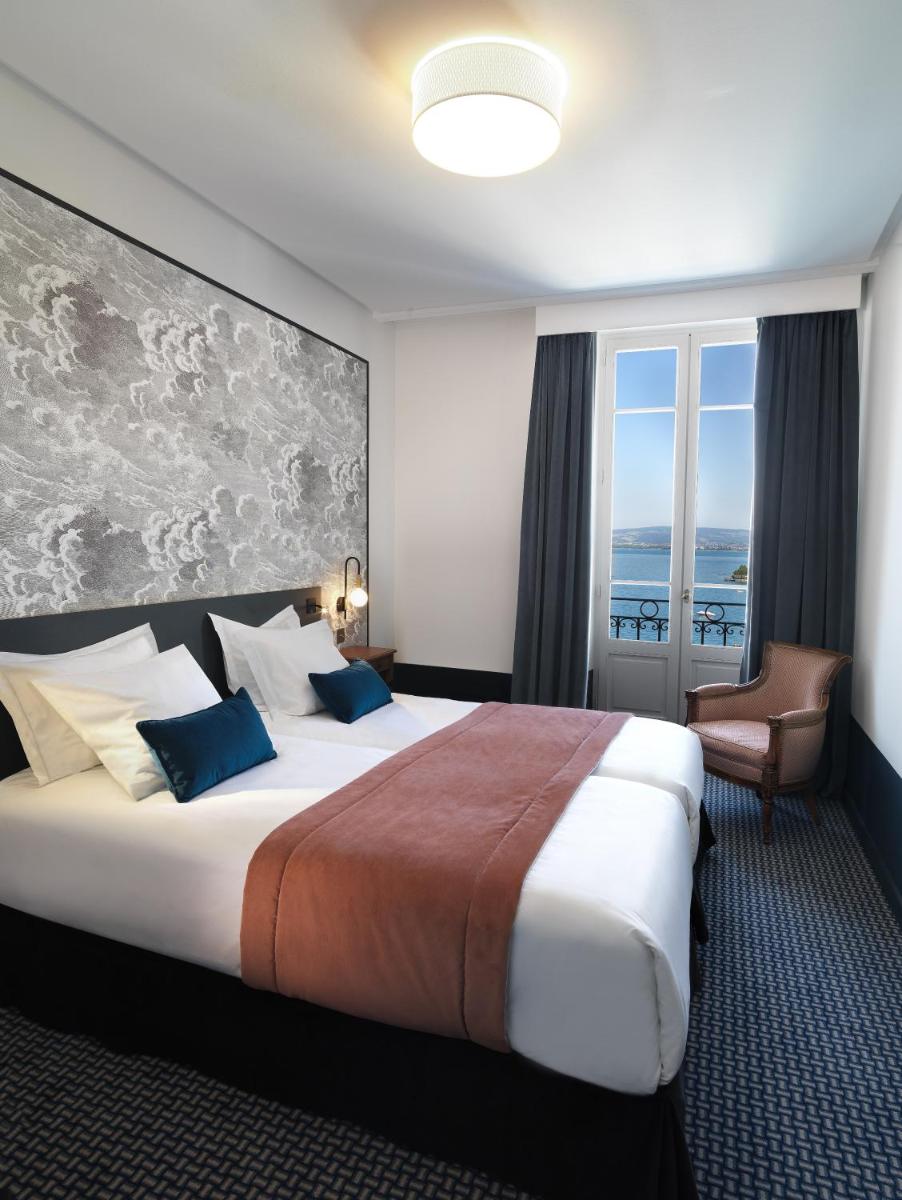 une chambre d'hôtel avec un grand lit et une fenêtre dans l'établissement Le Palace De Menthon, à Menthon-Saint-Bernard