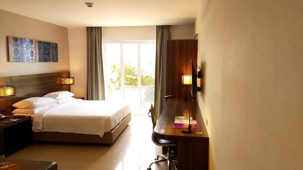 a hotel room with a bed and a desk and a window at The Residency Towers, Rameswaram in Rāmeswaram