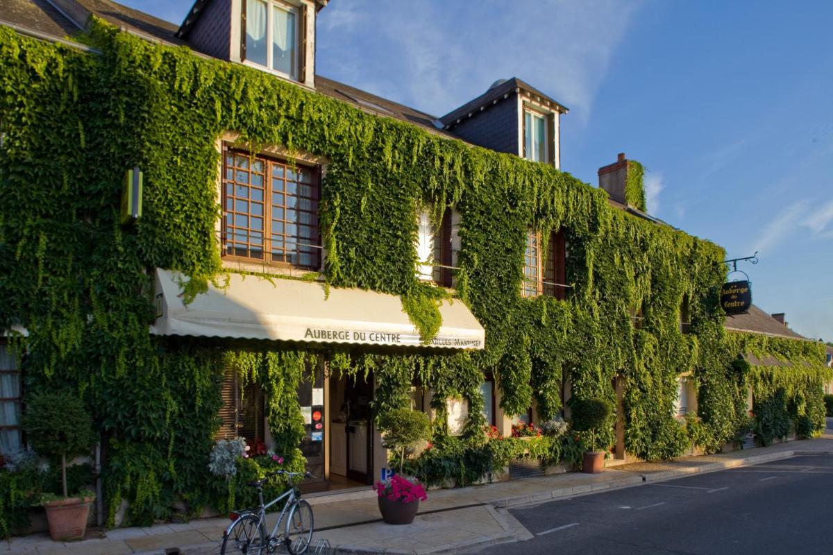 un bâtiment recouvert de lierre vert dans une rue dans l'établissement Logis Auberge Du Centre, à Chitenay