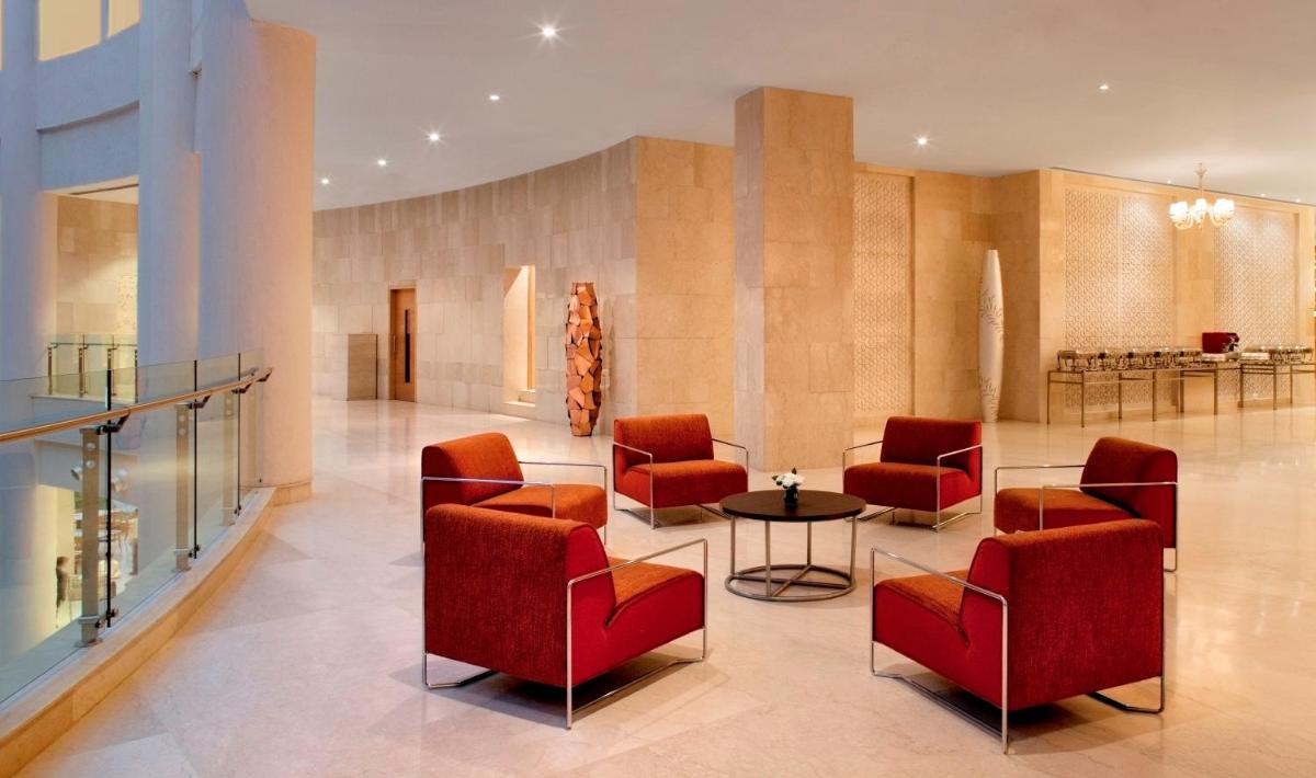 a lobby with red chairs and a table at Radisson Blu Hotel New Delhi Dwarka in New Delhi a lobby with red chairs and a table at Radisson Blu Hotel New Delhi Dwarka in New Delhi
