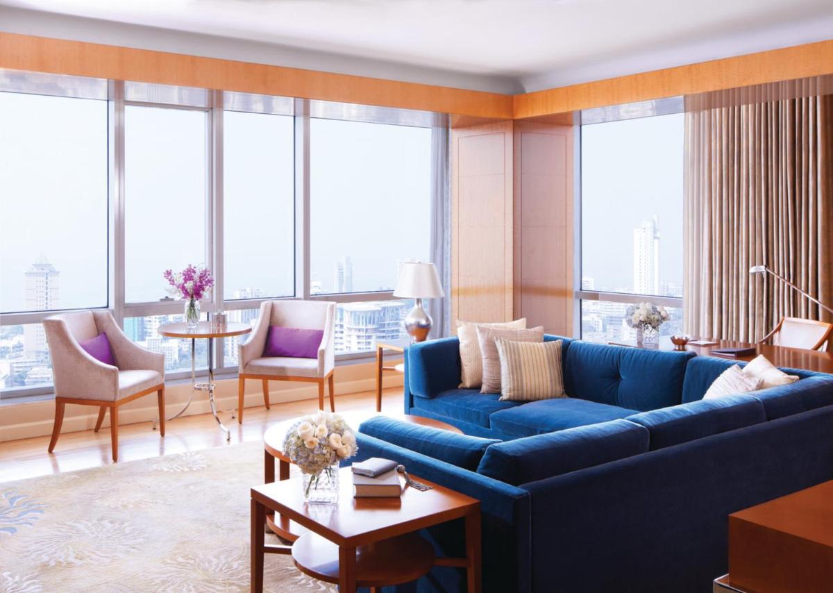 a living room with a blue couch and large windows at Four Seasons Hotel Mumbai in Mumbai