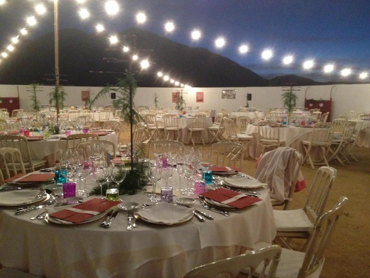 Un salón de banquetes con mesas y sillas blancas. en Cortijo Salinas, en Montecorto