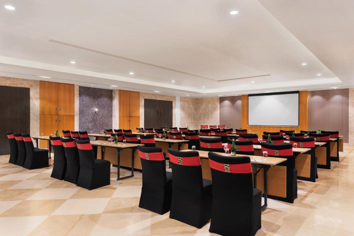 a conference room with tables and chairs and a screen at Ramada Plaza by Wyndham Lucknow in Lucknow