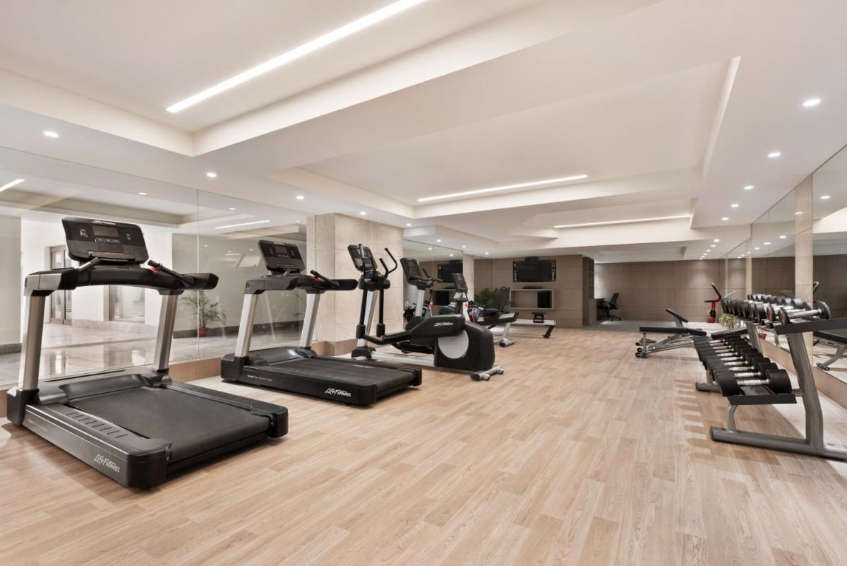 a gym with several treadmills and elliptical machines at Ramada Plaza by Wyndham Lucknow in Lucknow