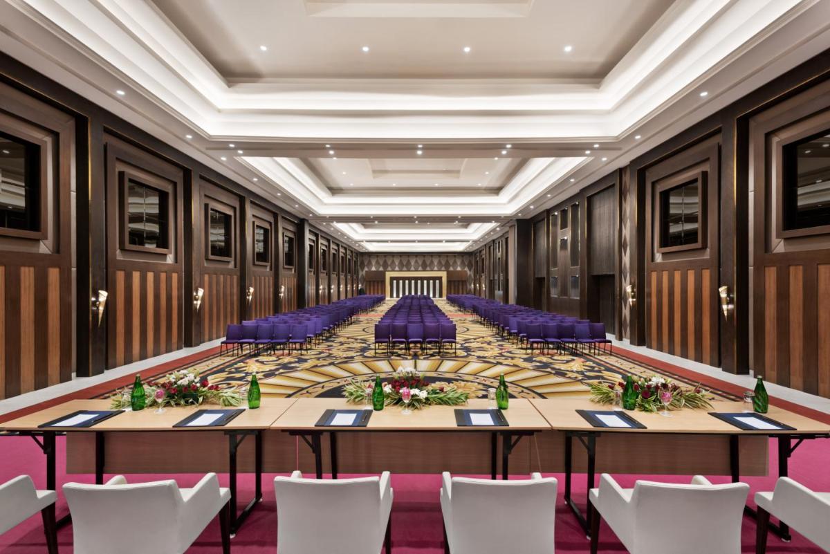 a large meeting room with a long table and purple chairs at Ramada Plaza by Wyndham Lucknow in Lucknow