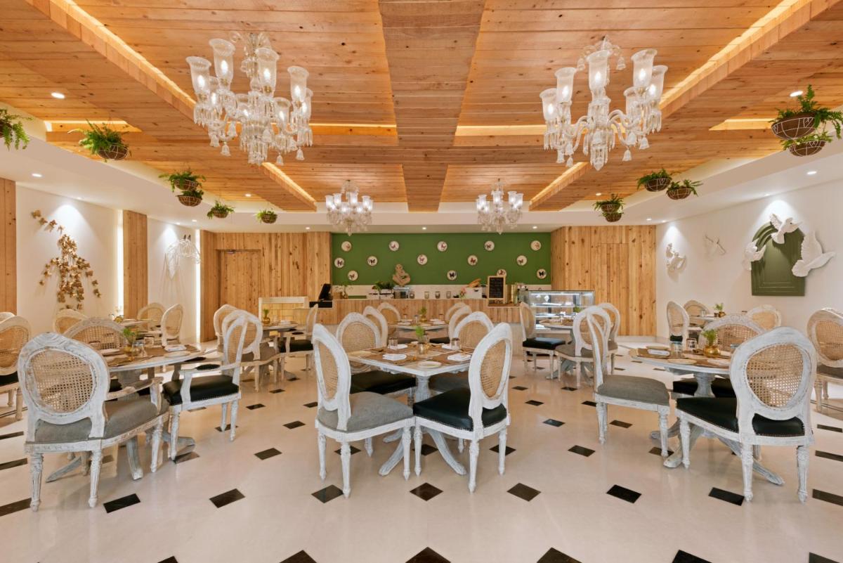 a dining room with tables and chairs and chandeliers at Ramada Plaza by Wyndham Lucknow in Lucknow