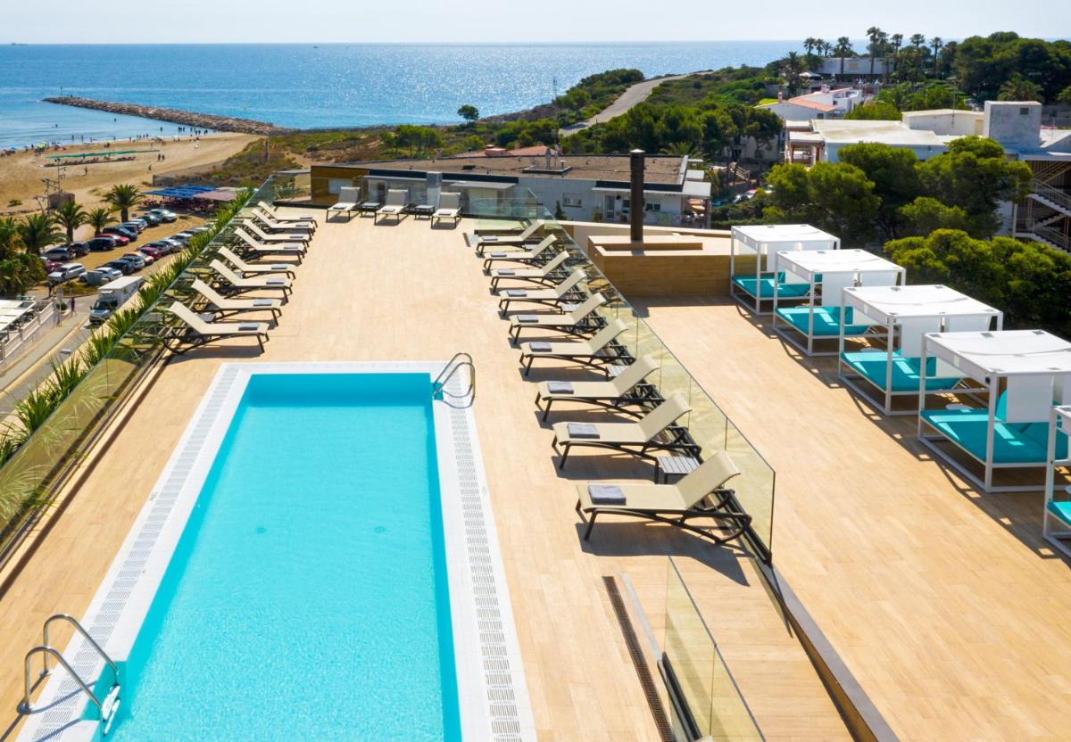 Una piscina con tumbonas y la playa. en Golden Costa Salou - Adults Only 4* Sup, en Salou
