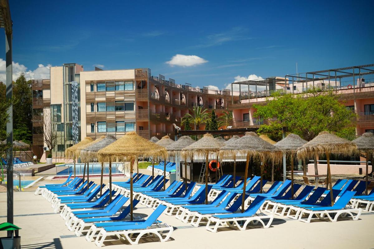 Una fila de tumbonas y sombrillas en una playa en Ohtels Les Oliveres, en Perelló