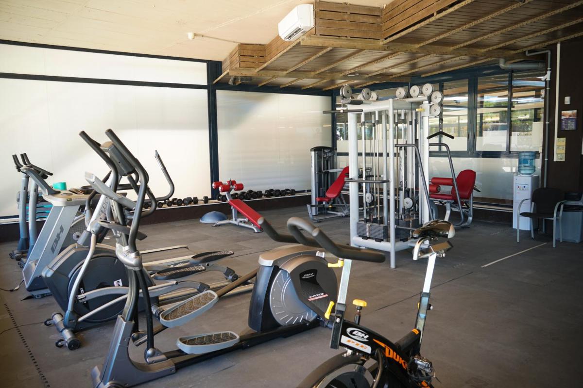 Un gimnasio con varias bicicletas cardiovasculares y máquinas de ejercicio. en Ohtels Les Oliveres, en Perelló