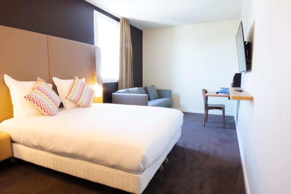 une chambre d'hôtel avec un lit et une chaise dans l'établissement Hotel Campanile Montpellier Centre St Roch, à Montpellier