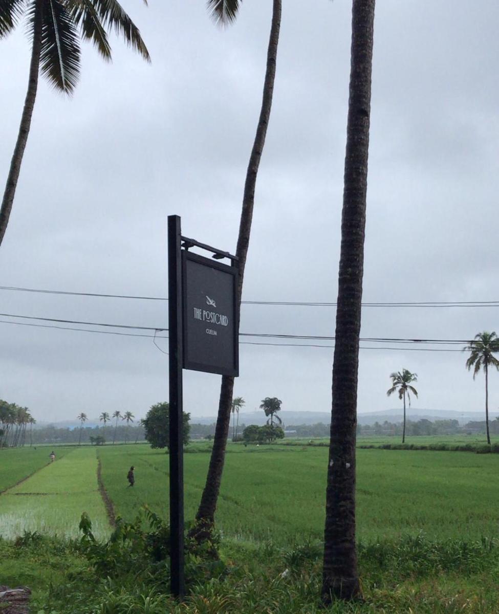a sign in front of a field with palm trees at The Postcard Cuelim, Goa in Cansaulim