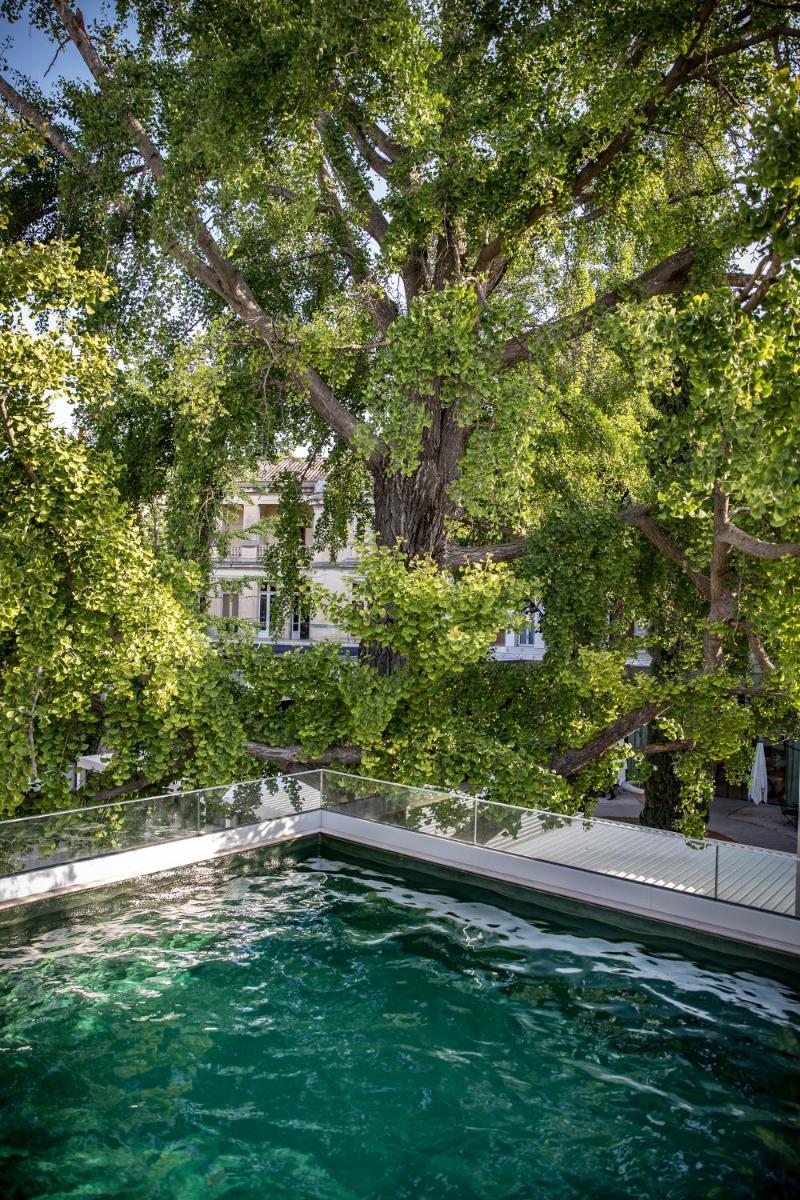 une piscine devant un immeuble avec des arbres dans l'établissement Maison Albar Hotels L’Imperator, à Nîmes