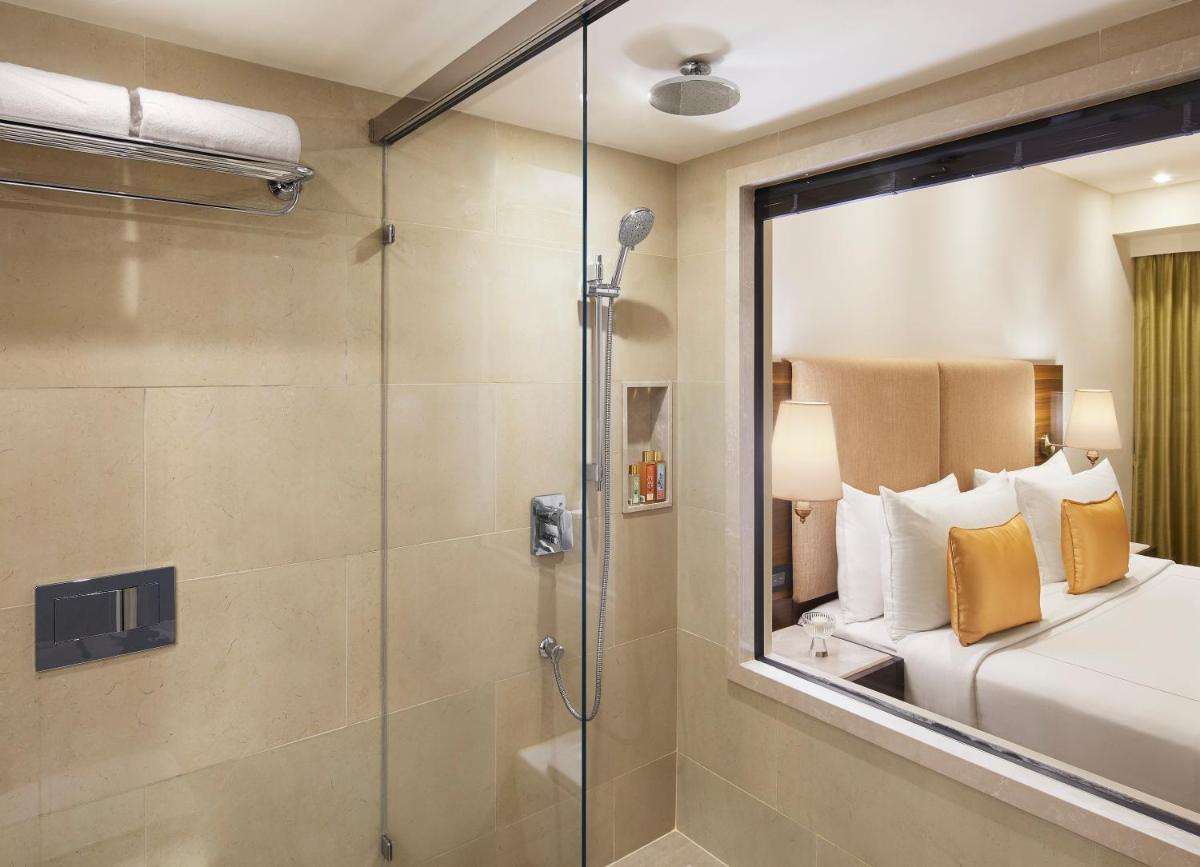 a bathroom with a shower and a bed and a glass shower stall at President - IHCL SeleQtions in Mumbai