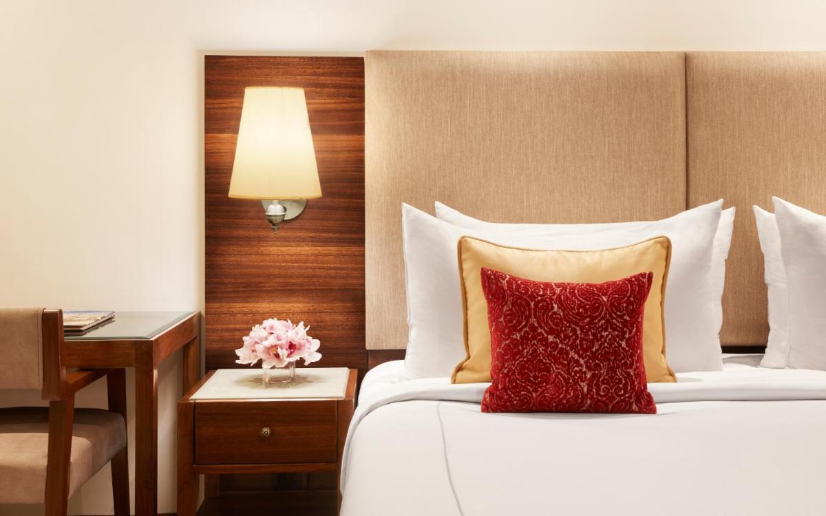 a bedroom with a bed with a red pillow and a desk at President - IHCL SeleQtions in Mumbai