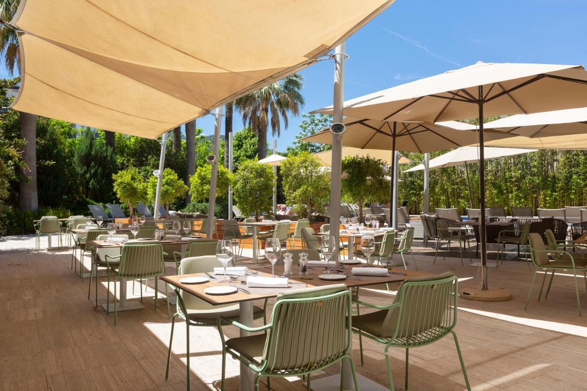 Un restaurante con mesas, sillas y sombrillas. en Aimia Hotel, en Puerto de Sóller