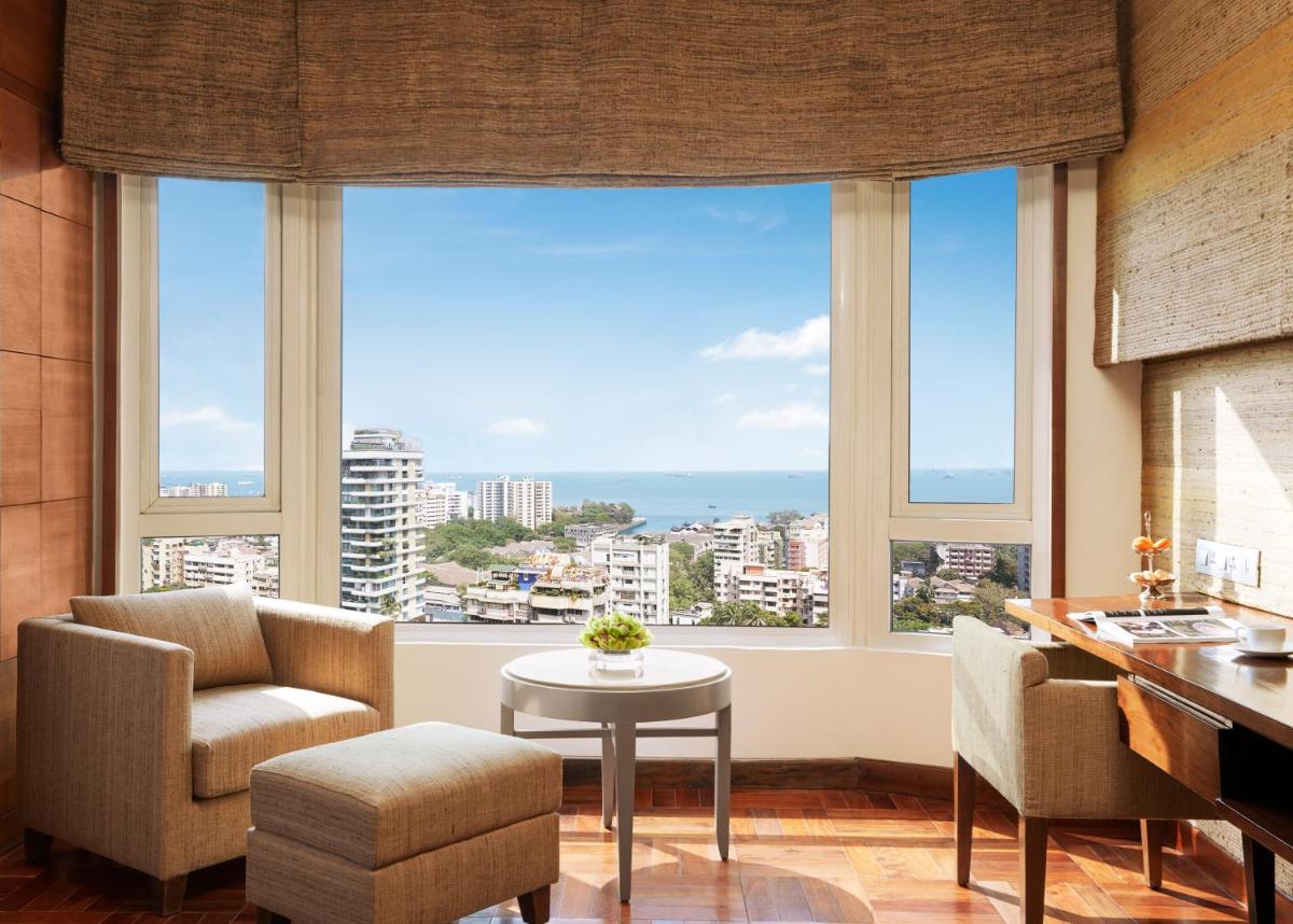 a living room with large windows and a table and chairs at President - IHCL SeleQtions in Mumbai