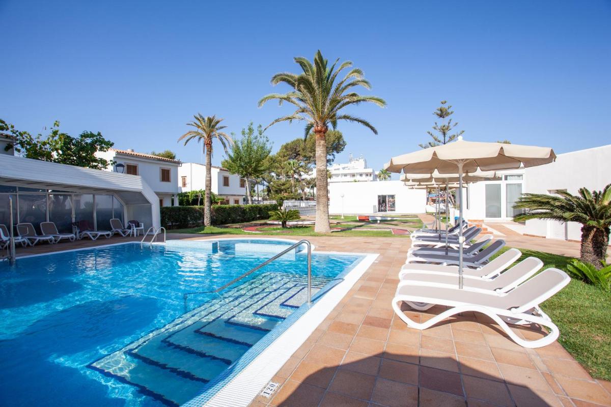una piscina con tumbonas y sombrilla en Grupotel Los Príncipes & Spa, en Playa de Muro