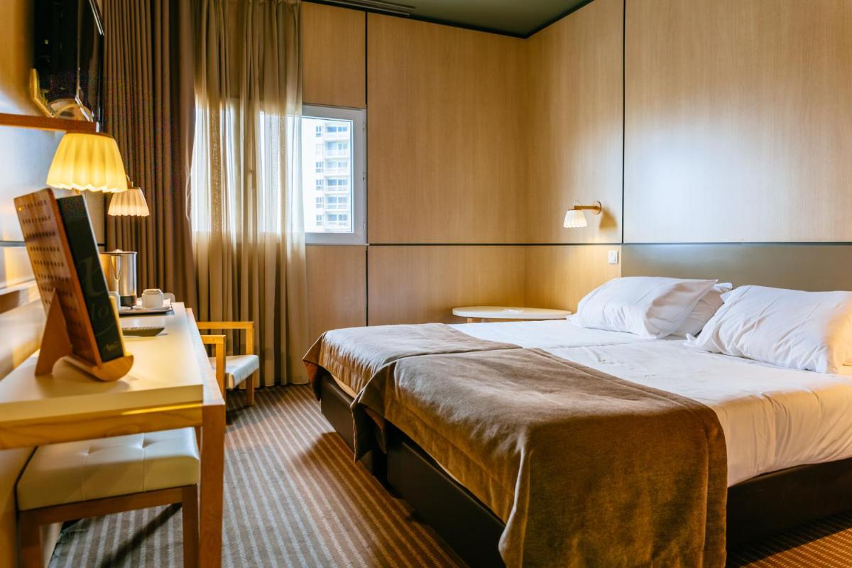 um quarto de hotel com uma cama grande e uma escrivaninha em Axis Vermar Conference & Beach Hotel na Póvoa do Varzim mais 55 fotografias