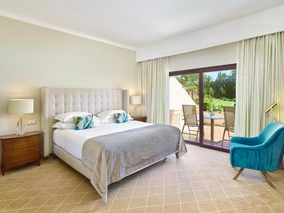um quarto com uma cama grande e uma cadeira azul em Hotel Quinta do Lago na Quinta do Lago