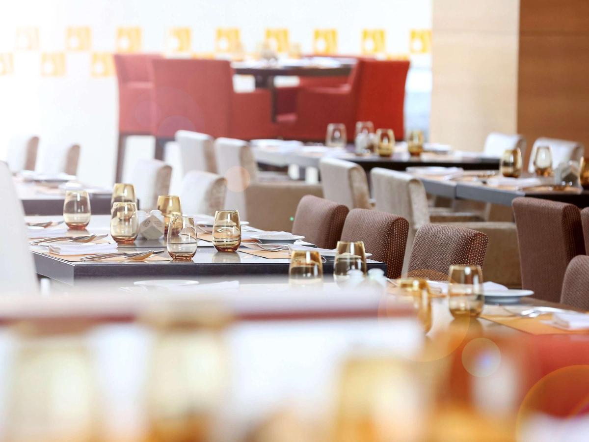 a dining room with tables and chairs with wine glasses at Novotel Pune Viman Nagar Road in Pune