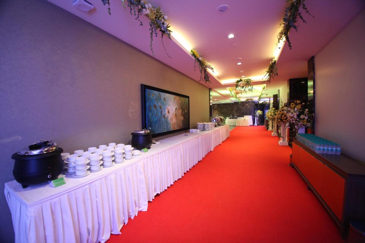 a corridor with a red carpet and a long table with white tables at Oakwood Residence Kapil Hyderabad in Hyderabad